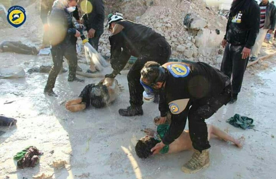 Syrian emergency workers in protective masks hose down kids after the attack 