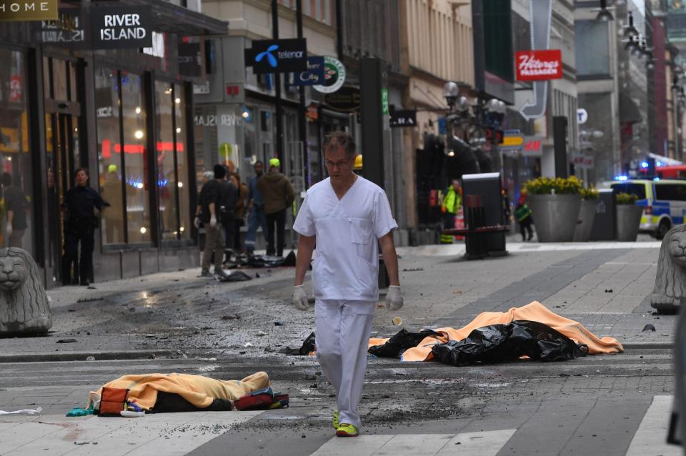 A medic walks through the streets, surrounded by the covered bodies of victims from the attack