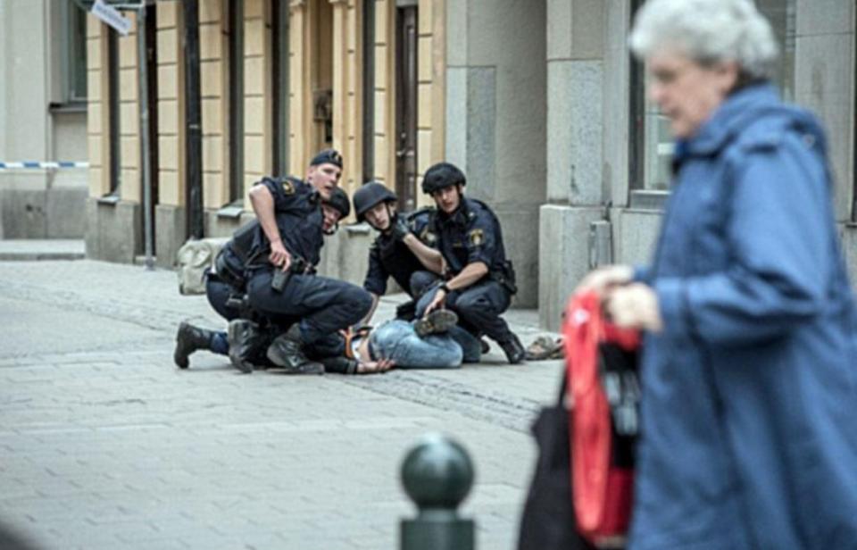 A person can be seen held on the ground by officers, with one seen holding his gun in its holster