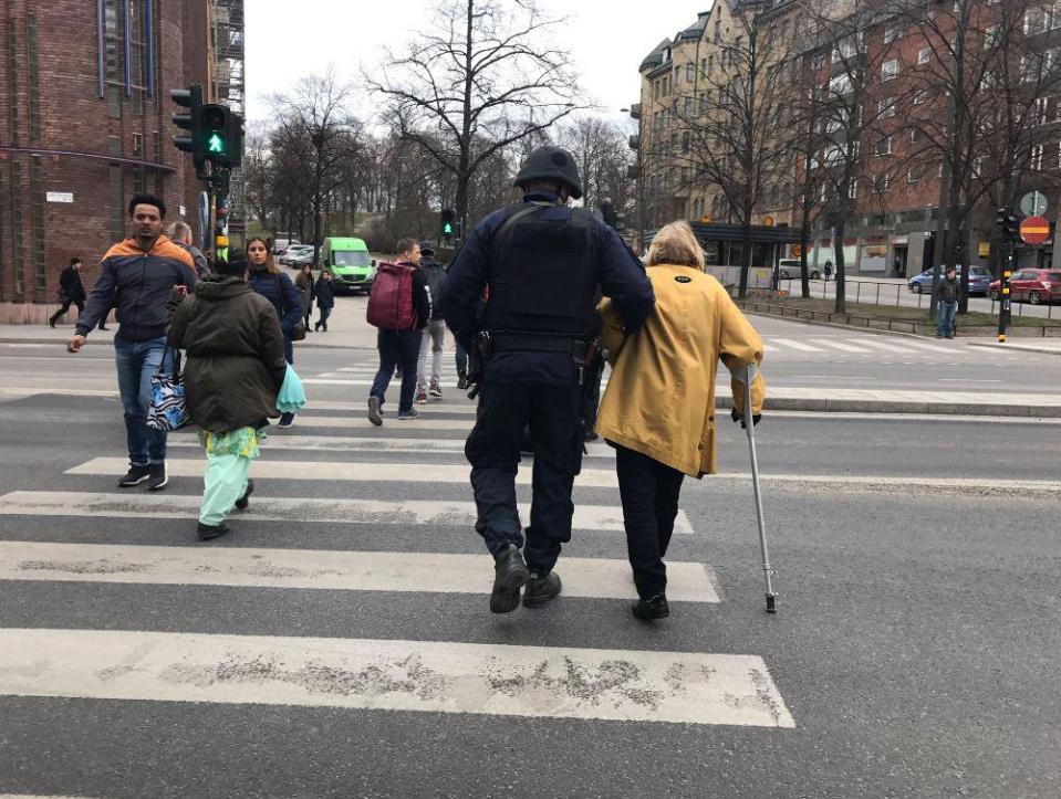 A police officer helps a woman cross a road int he aftermath of the terror attack