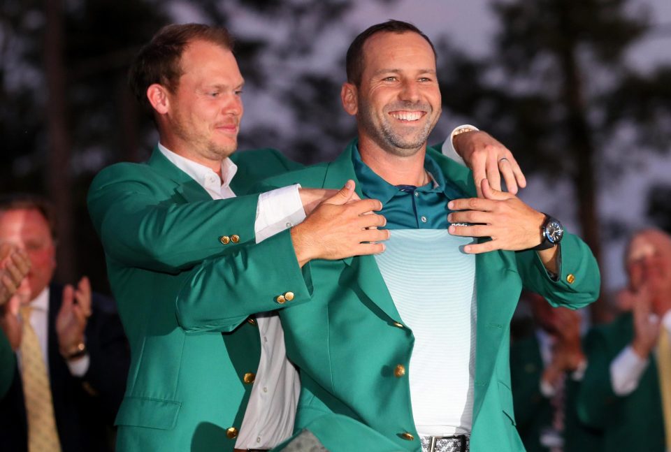  Danny Willett slips the green jacket onto Sergio Garcia