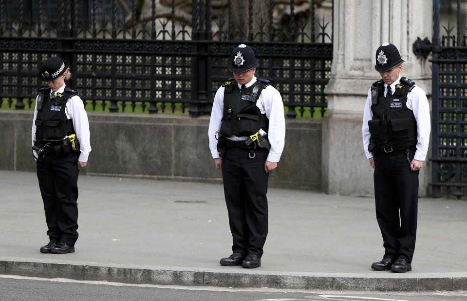 Police officers stand respectfully as the hearse containing PC Palmer moves off to Westminster