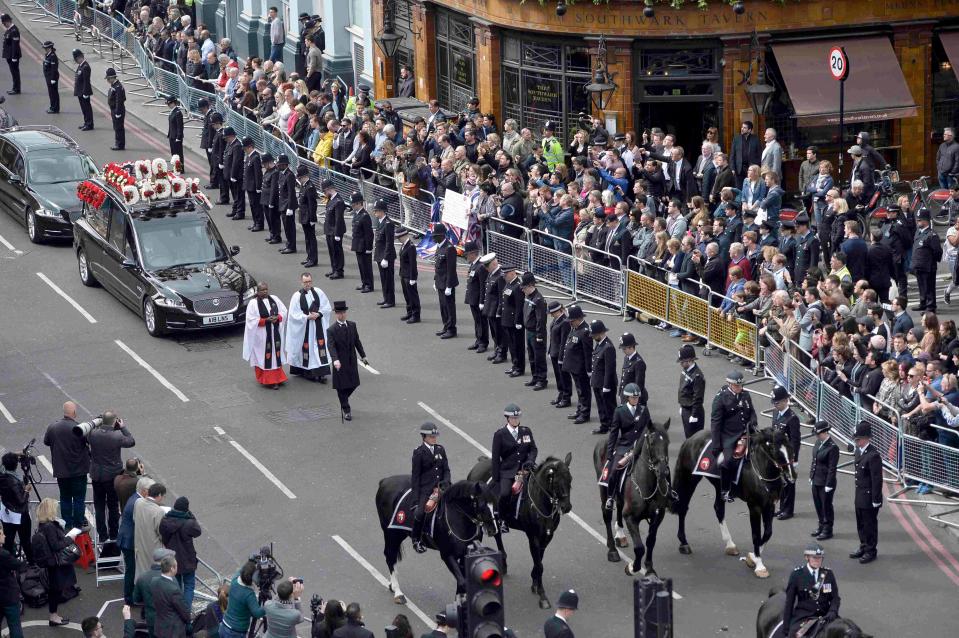 Police officers bow their heads as the hearse carrying PC Palmer drives by past rows of mourners