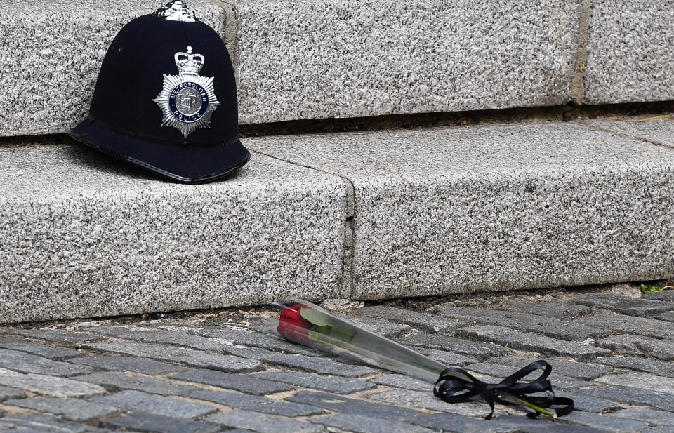 A single red rose is placed beside the police helmet of PC Keith Palmer 