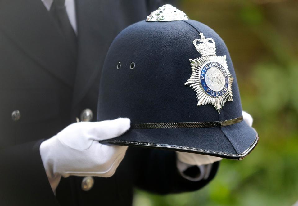 An officer carries the helmet of PC Keith Palmer into the Southwark Cathedral