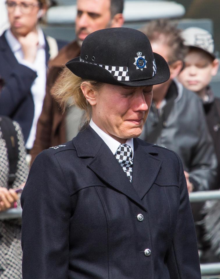 A female police officer sobs during the funeral procession 