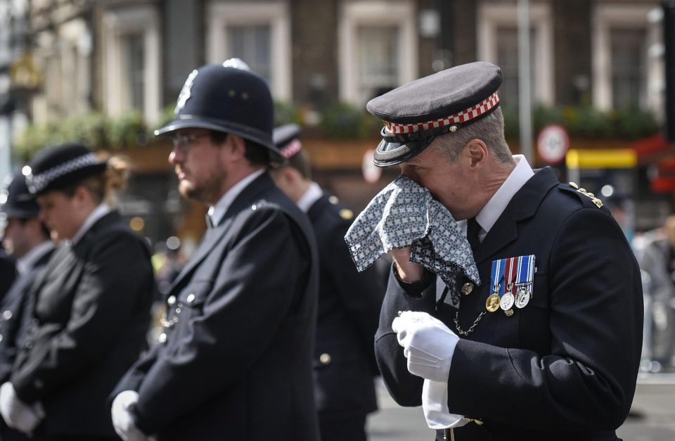 A police officer wipes away tears as he listens to the emotional funeral service for PC Palmer