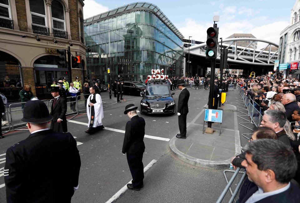 Officers bow their heads as the funeral cortege leaves Southwark following the funeral as PC Palmer is taken to a private cremation