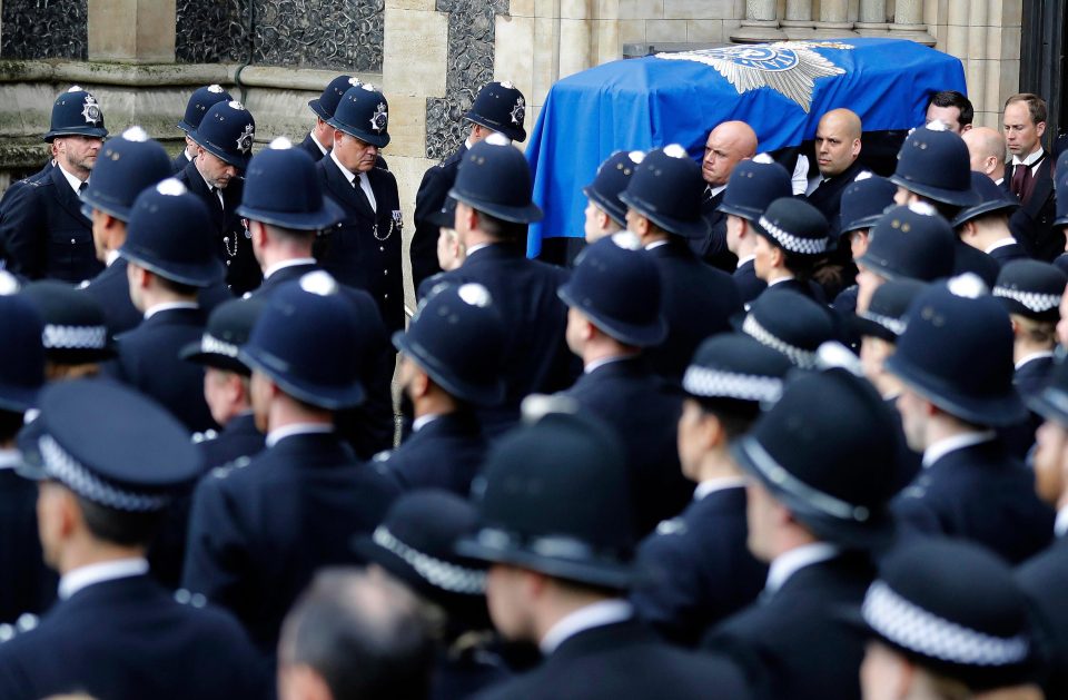 Officers bow their heads as his coffin is carried out of the cathedral ahead of the funeral service