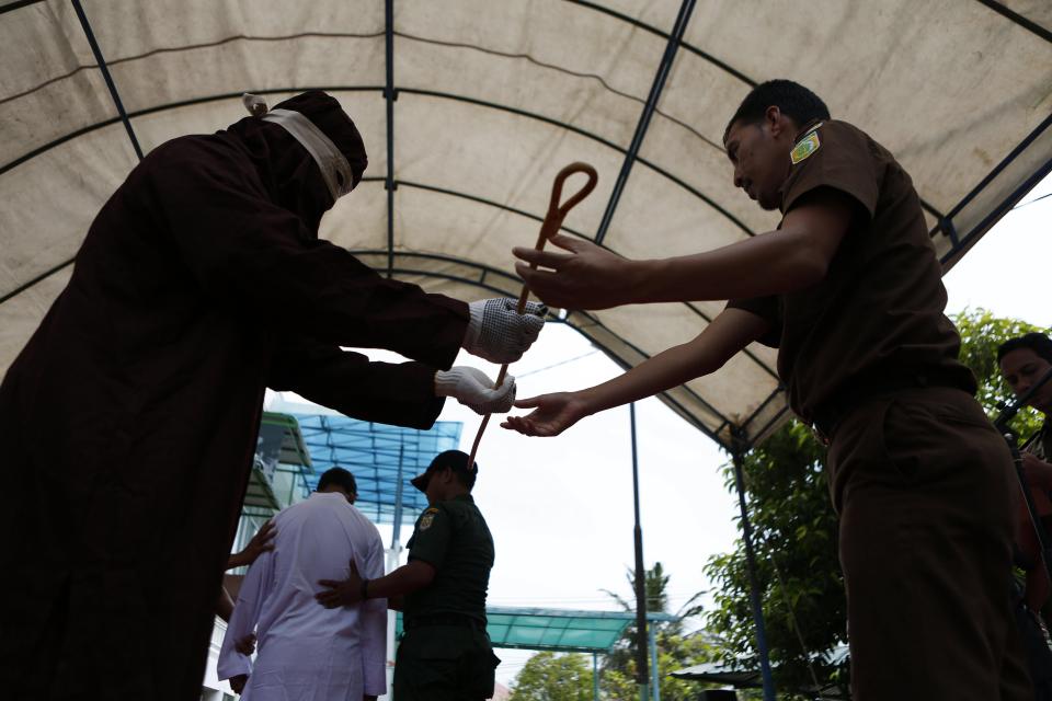  A sharia executor which is know as 'algojo' receives a rattan as a caning tool during a whipping punishment