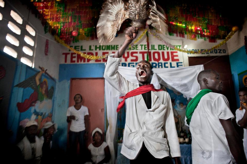  A man spins a chicken in the air, sacrificing to the spirits