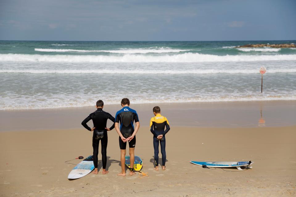  Surfers stand still on the Mediterranean Sea beachfront as a two-minute siren sounds in memory of victims of the Holocaust, in Netanya, Israel