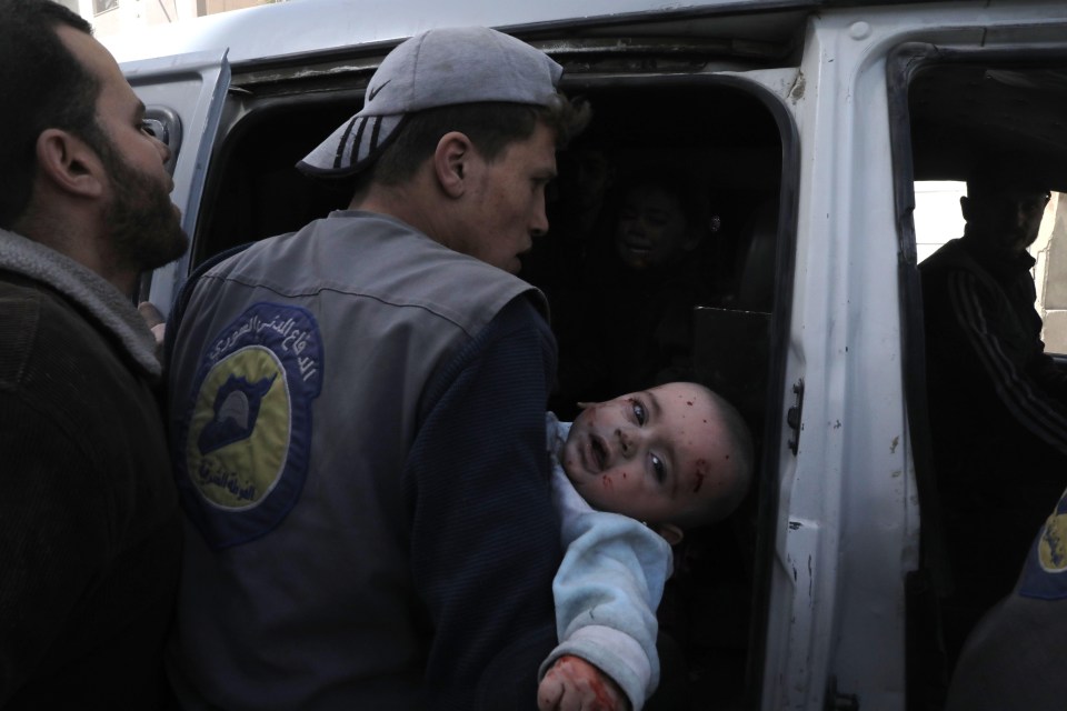 A Syrian civil defence volunteer carries an injured infant following Syrian government air strikes