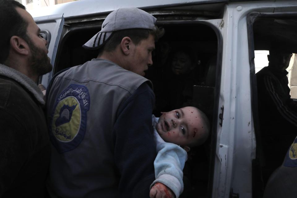  A Syrian civil defence volunteer carries an injured infant following Syrian government air strikes