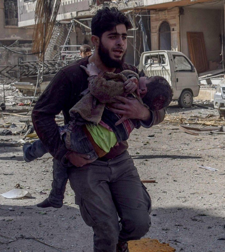 A Syrian man carries an injured child after Assad Regime forces carried out airstrikes in Eastern Ghouta’s Douma town in Damascus