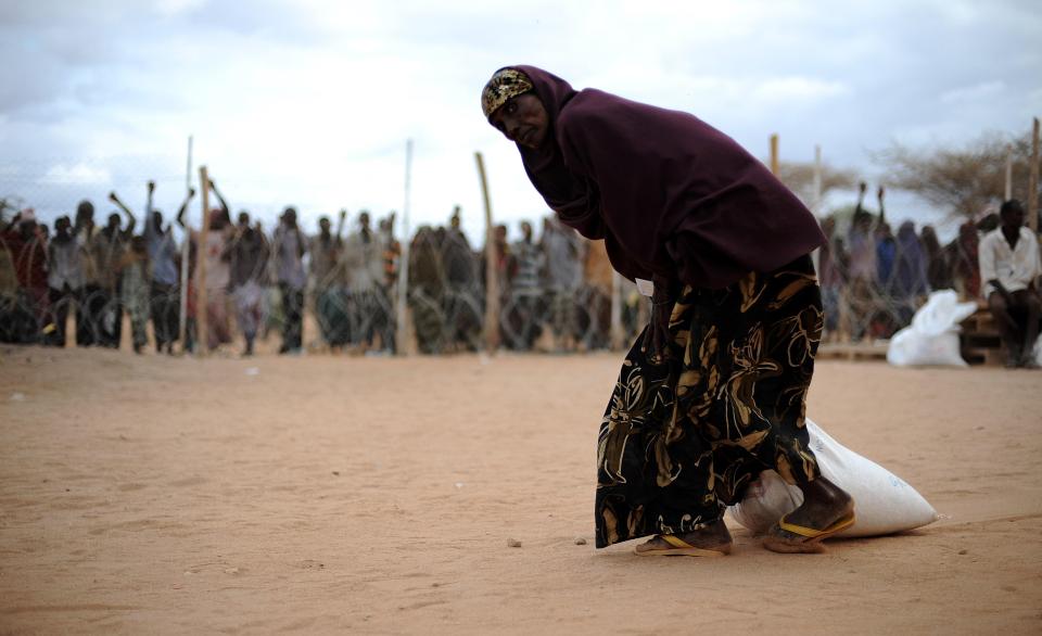  A Somali woman drags a sack of food aid at a refugee camp during the 2011 famine