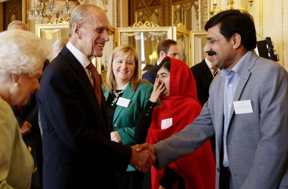  Malala Yousafzai laughs as she meets Prince Philip and he shakes her father's hand in 2013