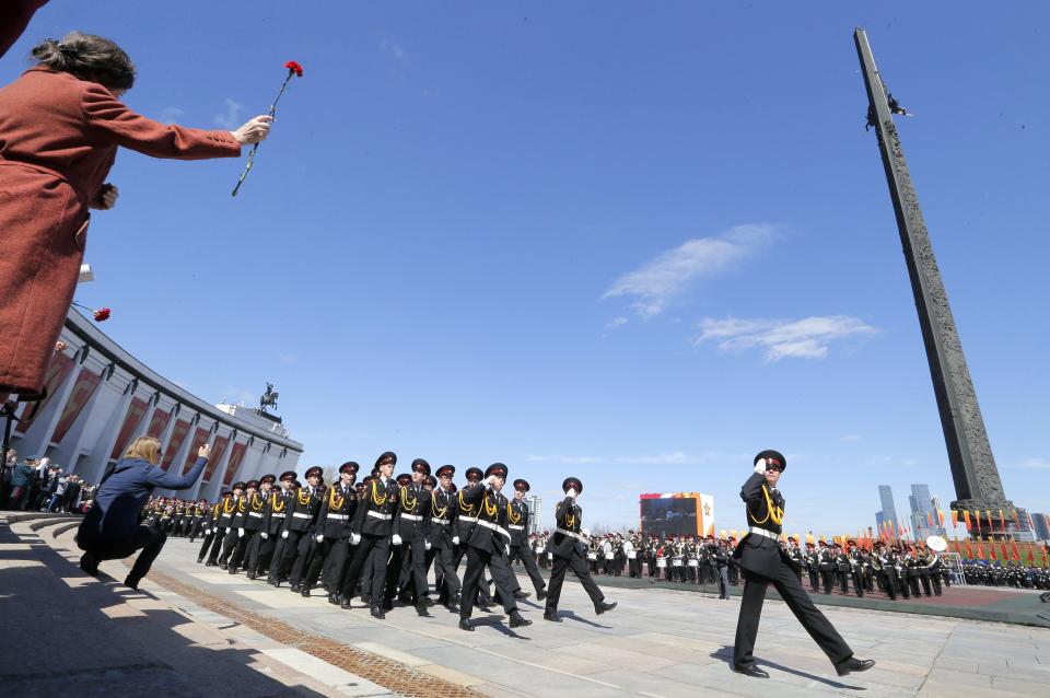  A local waves a single flower at the passing parade of troops in full military uniform