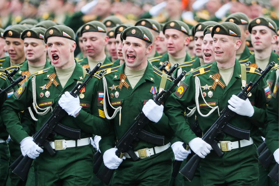  Servicemen clutching their rifles march through the city square