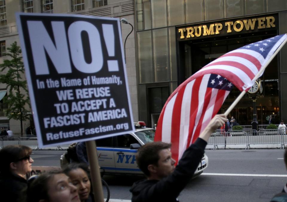  An American flag and an anti-Trump sign are held as people participate in a protest outside of Trump Tower in New York City