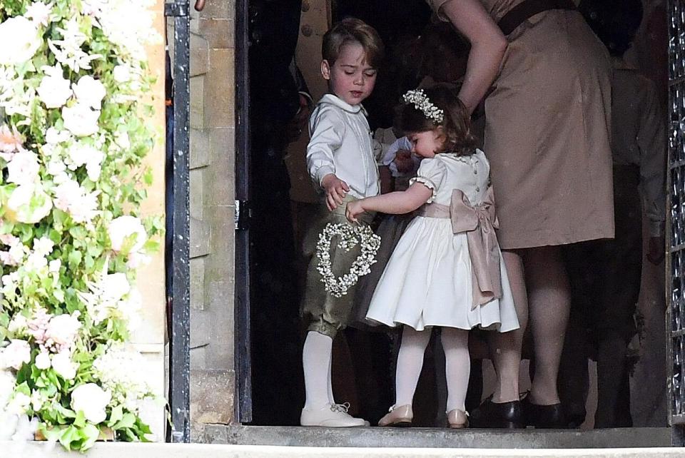  Page boy Prince George and his sister Charlotte, who is bridesmaid, hold hands as they join their aunt's wedding