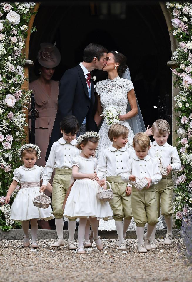  Newly married James Matthews and Pippa Middleton kiss as they stand outside the picturesque church behind the adorable flower girls and page boys