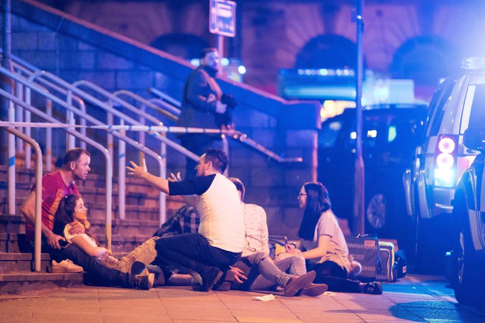 Bloodied fans lay on the ground outside the venue in shock after fleeing the city centre arena