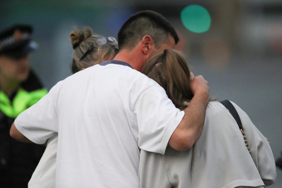  A man embraces a woman and a teenager as he collects them from the Park Inn Hotel where they were given refuge after last night's explosion