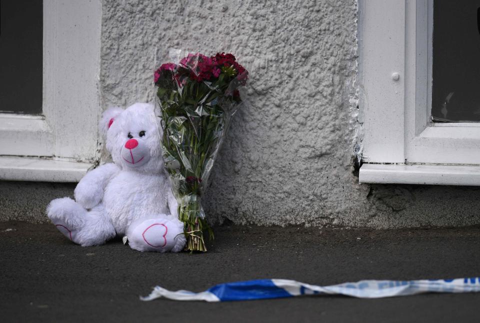 A floral tribute and a teddy bear are pictured alongside police tape near to the Manchester Arena