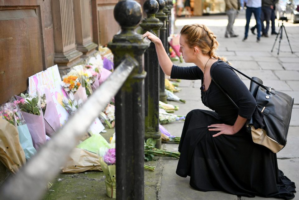 A woman lays flowers for the victims in St Ann Square, Manchester, today