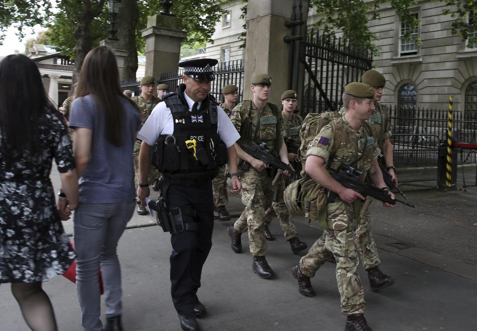  Armed police and British soldiers march through an entrance into Buckingham Palace in the wake of the Manchester attack