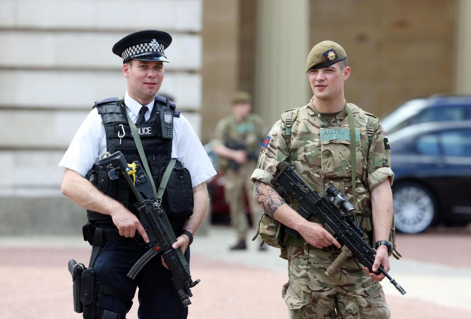  An armed officer and an armed soldier stand together as they guard Downing Street