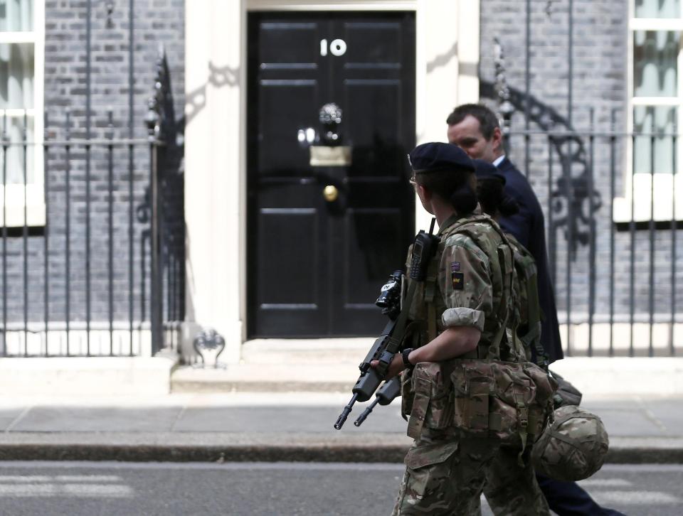  An armed soldier escorts a man as they walk past Number 10 Downing Street