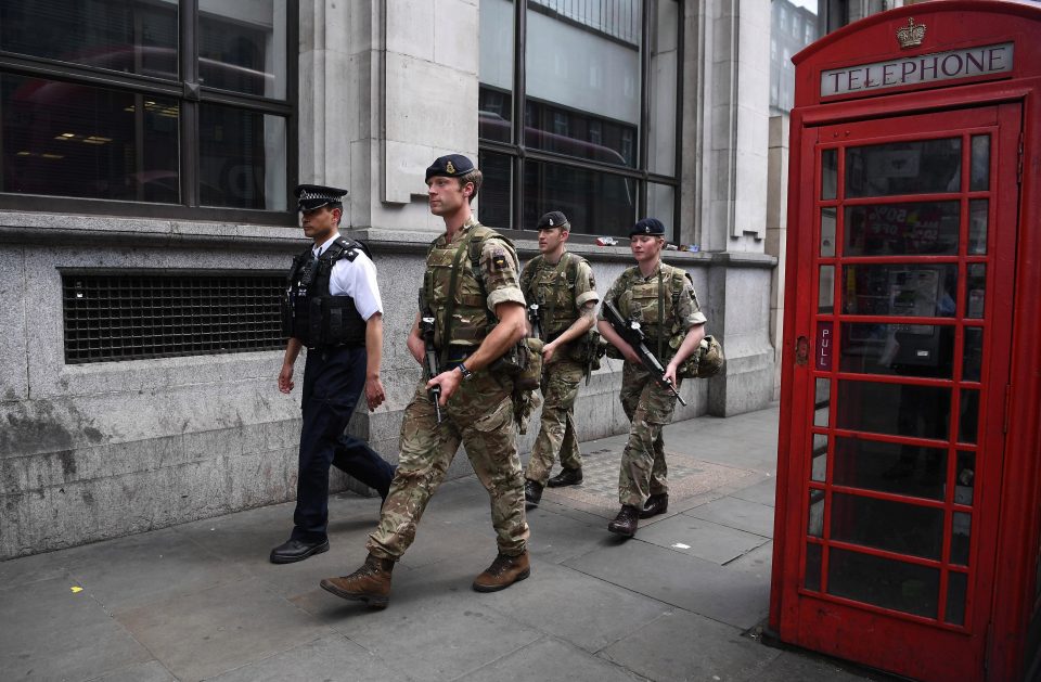  Armed police and soldiers patrol the streets of London as they walk by an iconic red telephone box