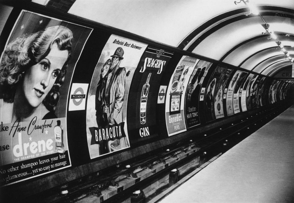  Shampoo, raincoats and gin are some of the products advertised in the posters that line the tunnel wall at the Piccadilly underground station in 1949