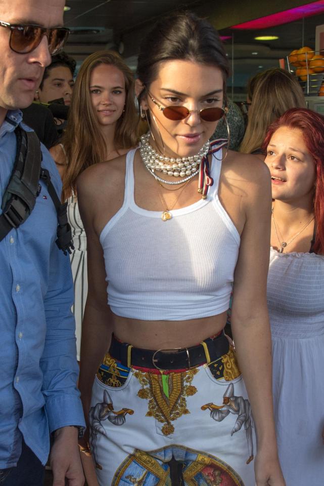  Kendall Jenner braless in a white crop top which she wore with colourful print trousers