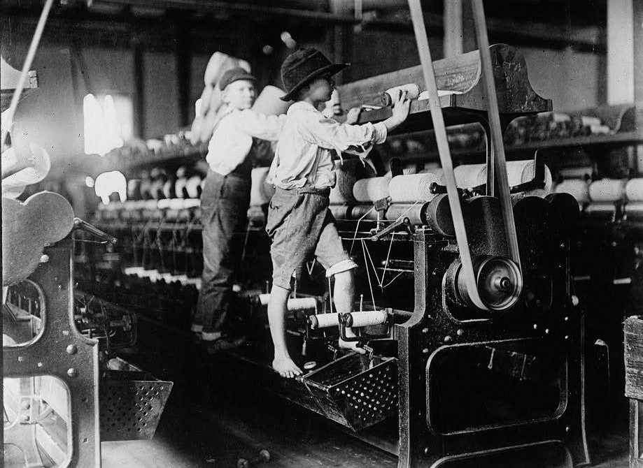  Tiny mill kids who could be as young as seven clamber barefoot onto the dangerous machines to change the reels of cotton in 1909