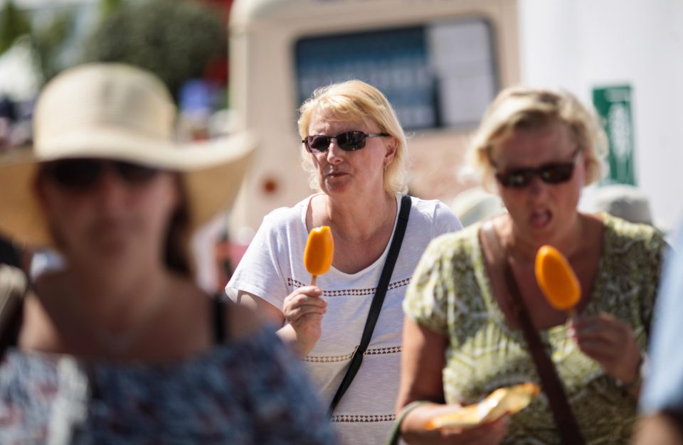  Visitors eat ice lollies as they walk through the grounds of the Chelsea Flower Show on Thursday