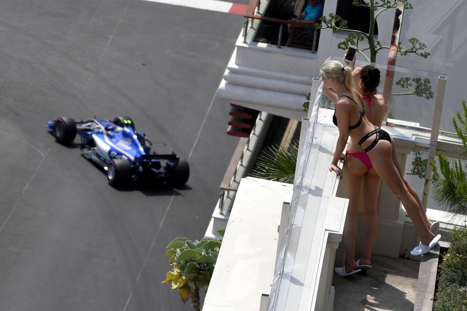  Two sunbathers peer over a balcony as German driver Pascal Wehrlein races by