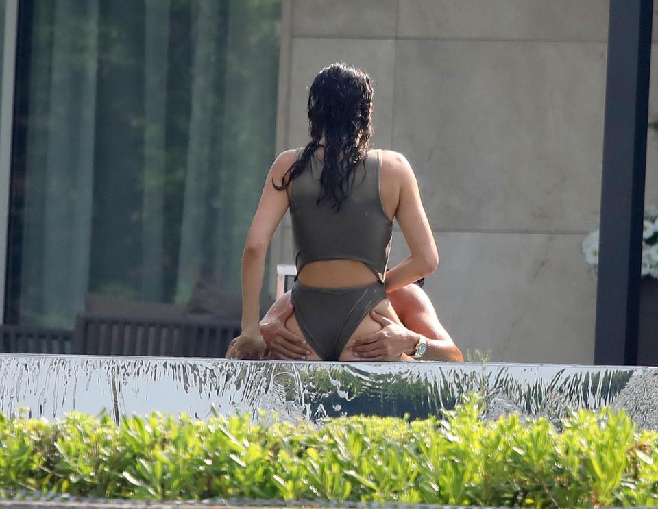  He placed his hands on her bum as she sat up on the ledge of the pool