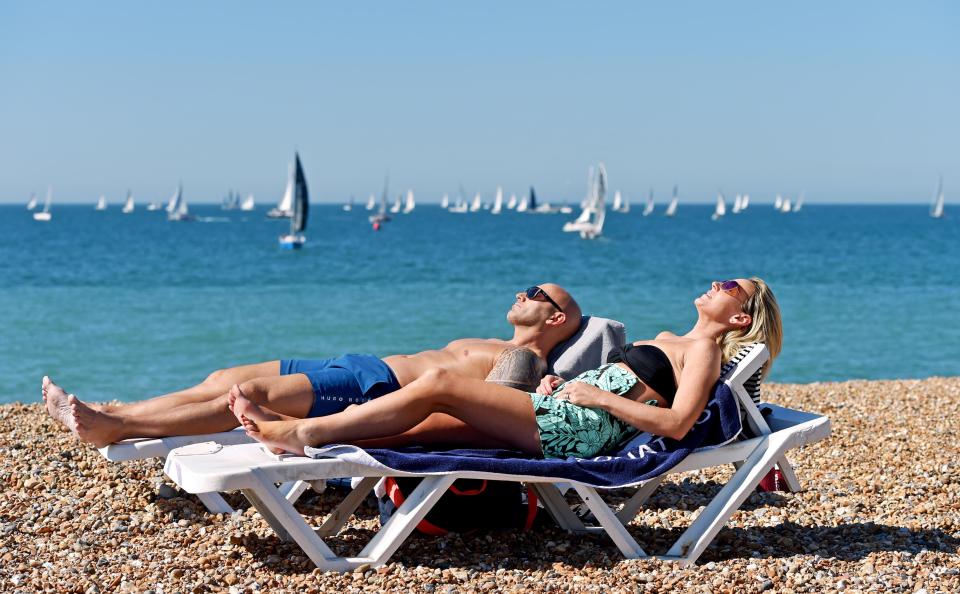  A couple enjoy some early morning sunbathing on Brighton beach