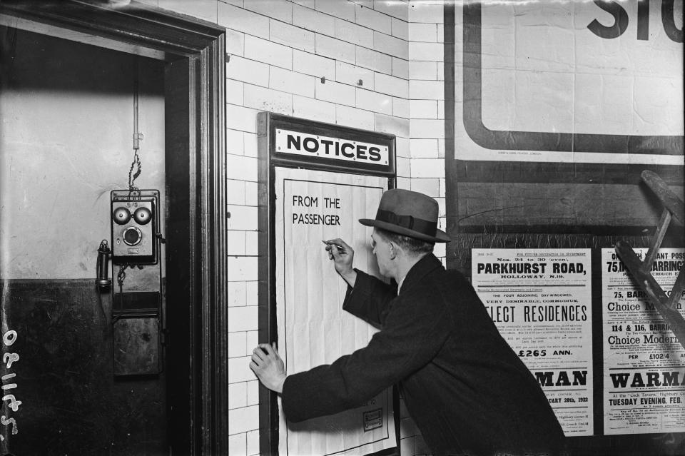  A man writing on a complaints poster on the London Underground