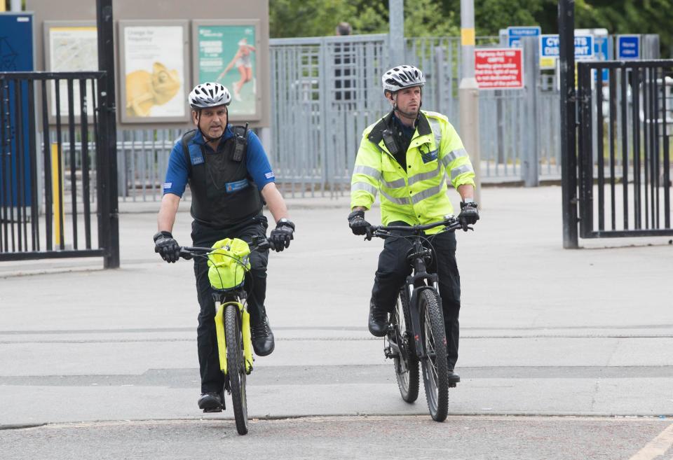 Police community support officers arrive on bikes at the Old Trafford Cricket Ground during the setting up for the concert