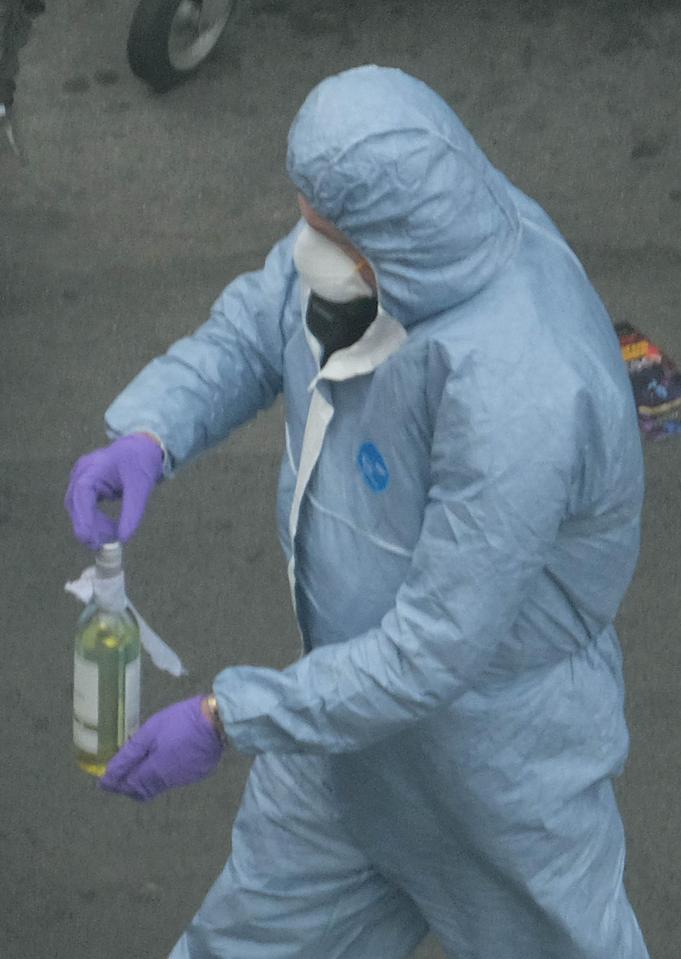  A forensic officer seen carrying what appears to be a glass bottle with a rag tied around the top