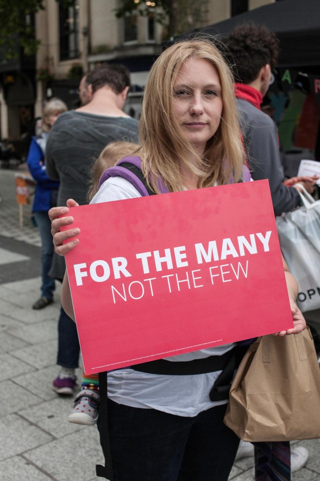 A protester points out that the many should be served by government, rather than the few