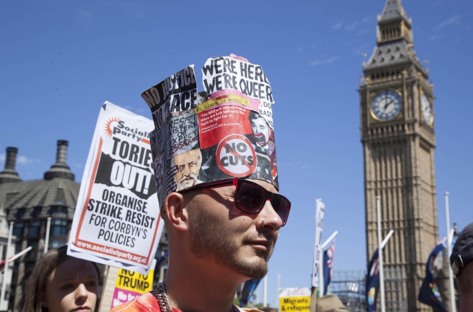 A protester stands near Big Ben, wearing a hat calling for no cuts