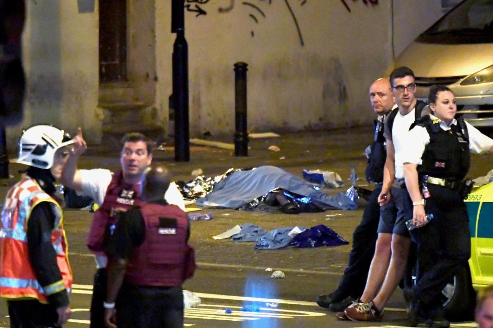  A body is covered with a sheet in the middle of the road as officers carry out an emergency response