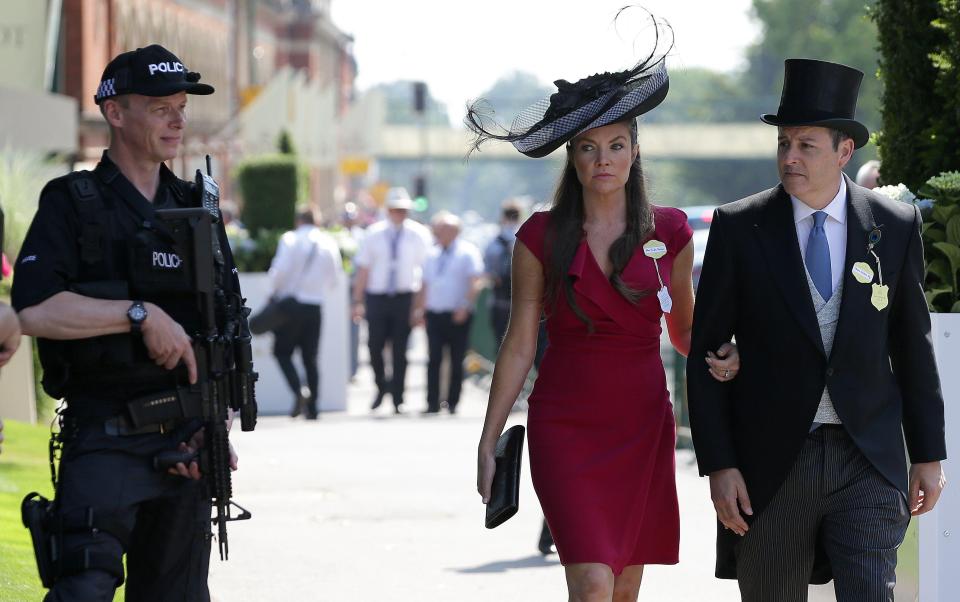  A gun cup stands guard as a smartly-dressed couple enjoys the first day of this year's Ascot festival