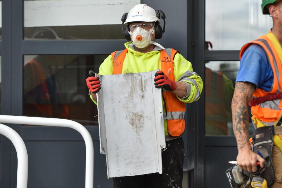  A worker is seen holding cladding removed from Silverwood House in Doncaster