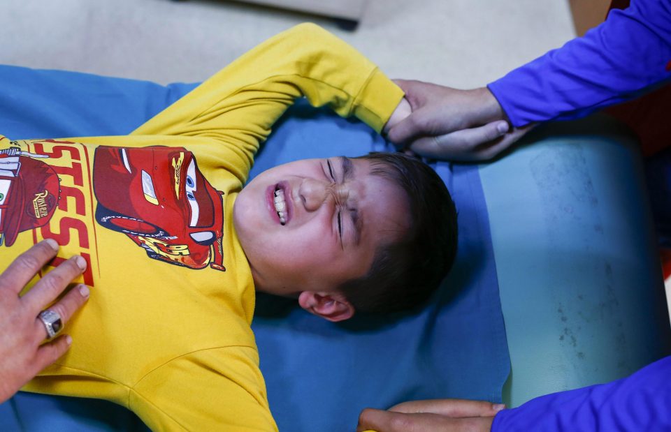  An adult holds each boys arms while a licensed practitioner makes the incision